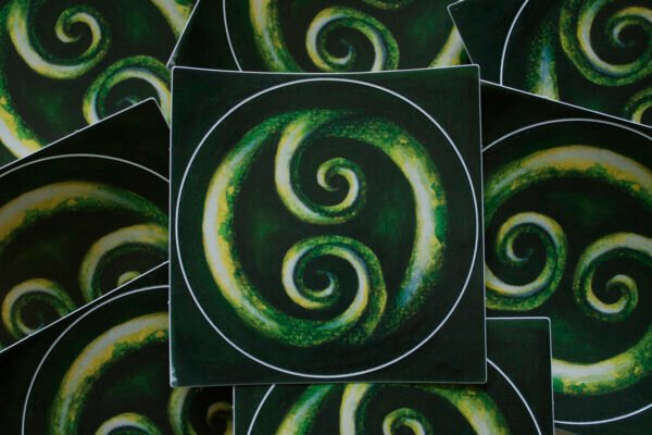 Round Double Koru Sticker lying on other green koru stickers with colour inspired by the precious New Zealand greenstone