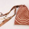 Brown handprinted fabric drawstring bag with ripple tree ring print closed with colourful ribbons and beads splayed out