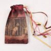Burgundy handprinted fabric drawstring bag with Cat Goddess print closed with colourful ribbons, charms and beads splayed out
