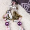Close Up of Druid Tree Pouch showing grey, purple, silver ribbons, pearlesque plastic beads and metal triskele charms