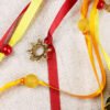 Close Up of Glastonbury Tor Pouch with red, yellow and orange ribbons, yellow and red plastic beads and gold metal sun charms