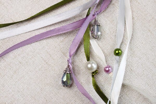 Close Up of rose pentagram Pouch with purple, white, grey, green ribbons, pearlesque plastic beads and metal glass bead charm