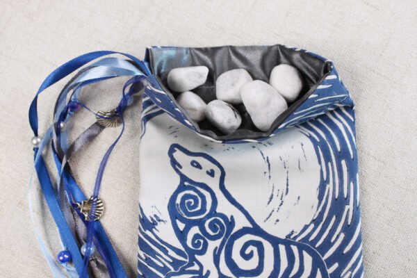 White cotton Selkie Beast pouch with dark grey poly-satin lining, white rune stones spelling Imogen are sitting in pouch