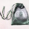 Green handprinted fabric drawstring bag with Moon Gate and Stars print closed with colourful ribbons and beads splayed out